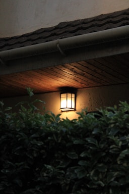 An elegant aluminum outdoor wall lantern casting a warm glow on a cozy patio