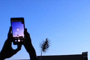 A person using a smartphone outdoors with a city skyline in the background