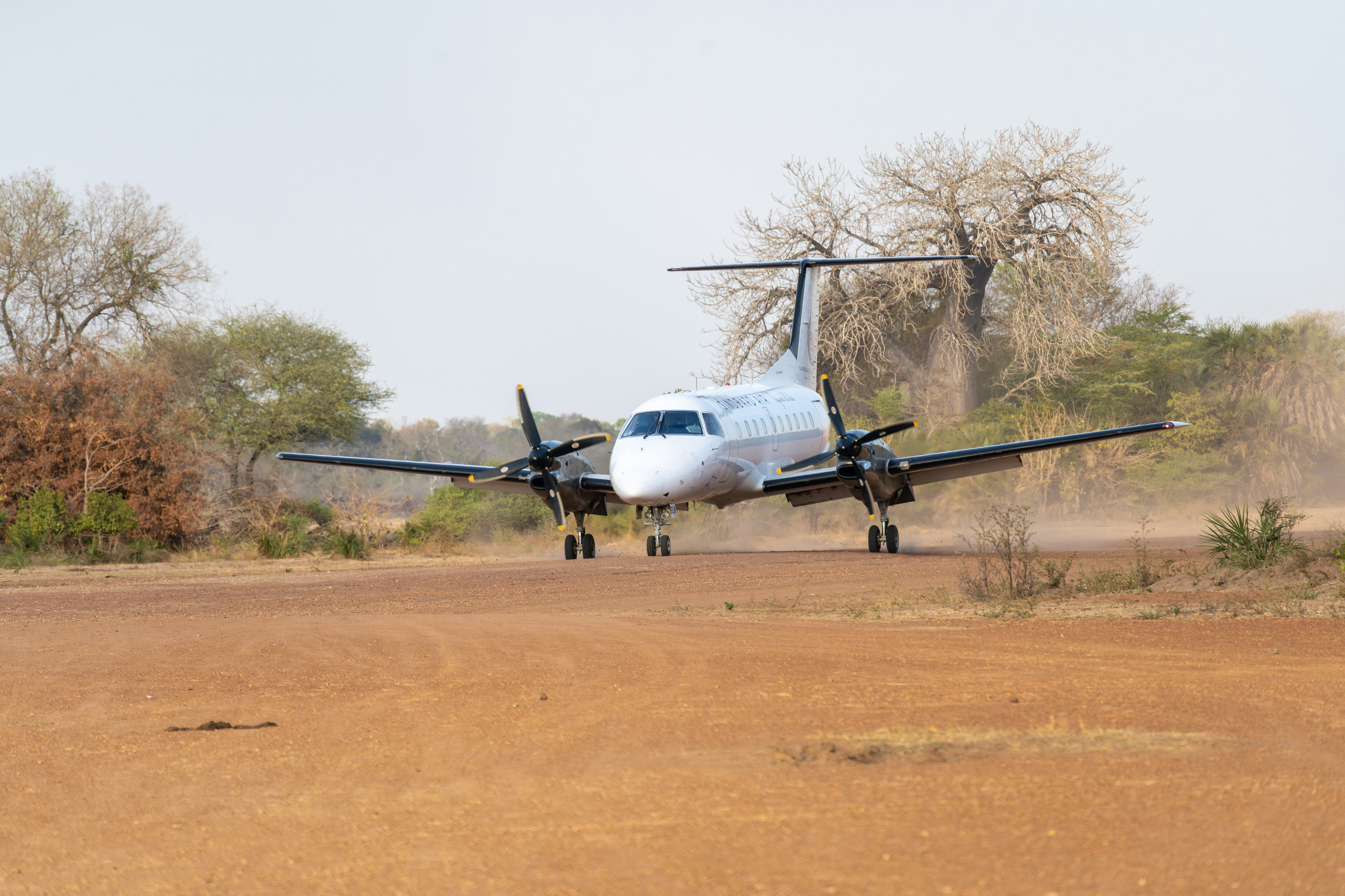 a small plane landing on a dirt runway, An Embraer 120 operated by Sindbard Air touching down on Mtemere Airstrip, Tanzania.
