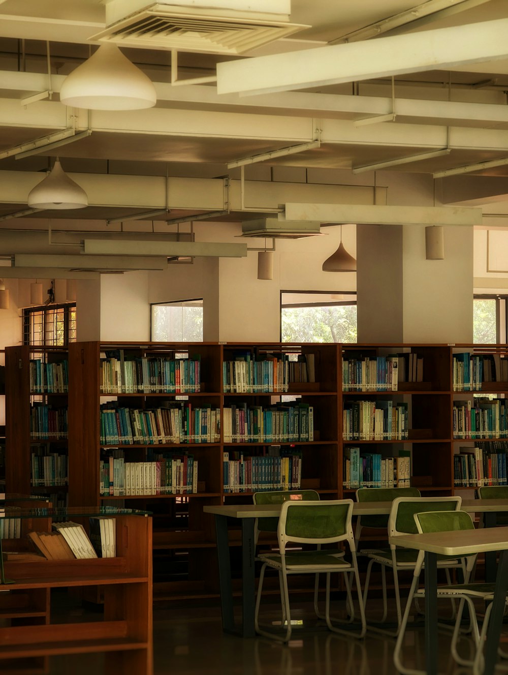 a library filled with lots of books and lots of green chairs