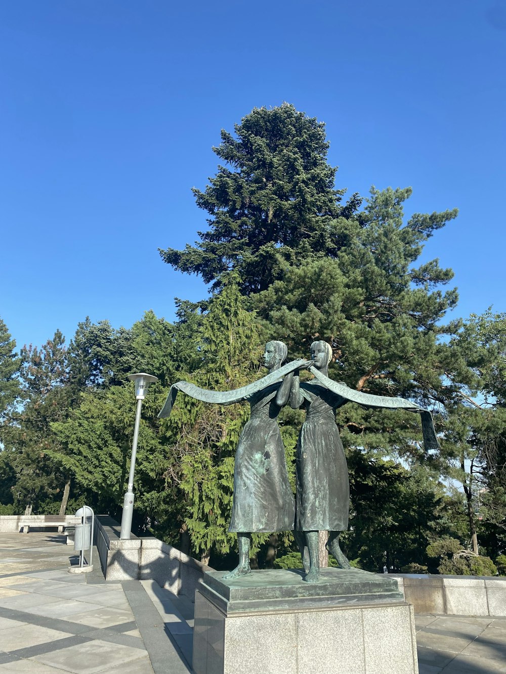 a statue of two people holding hands in front of a tree