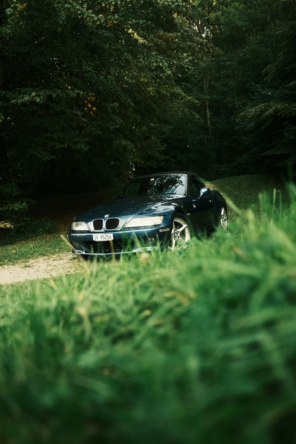 a car parked on a dirt road in the woods