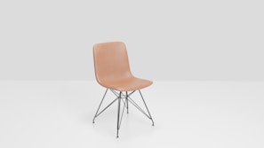 A tan molded plastic chair with a minimalist design sits on black metal legs with cross-bracing. The background is a simple light gray, enhancing the chair's modern aesthetic.