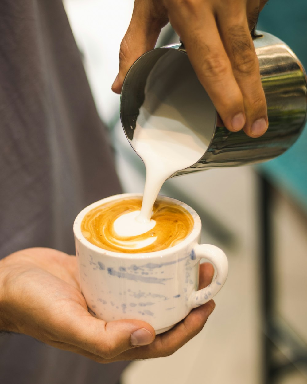 a person pouring milk into a cup of coffee