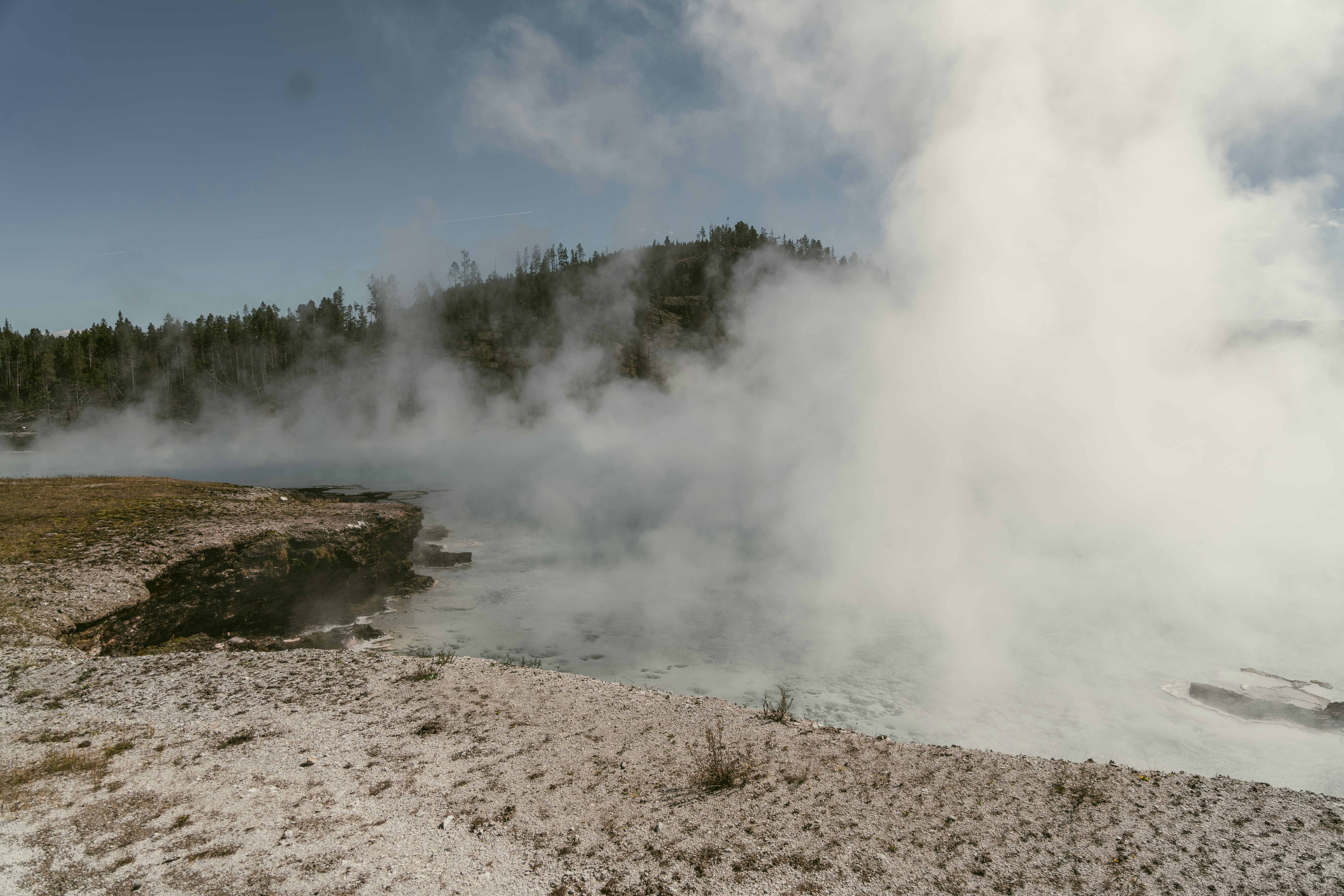 steam rises from the ground near a body of water