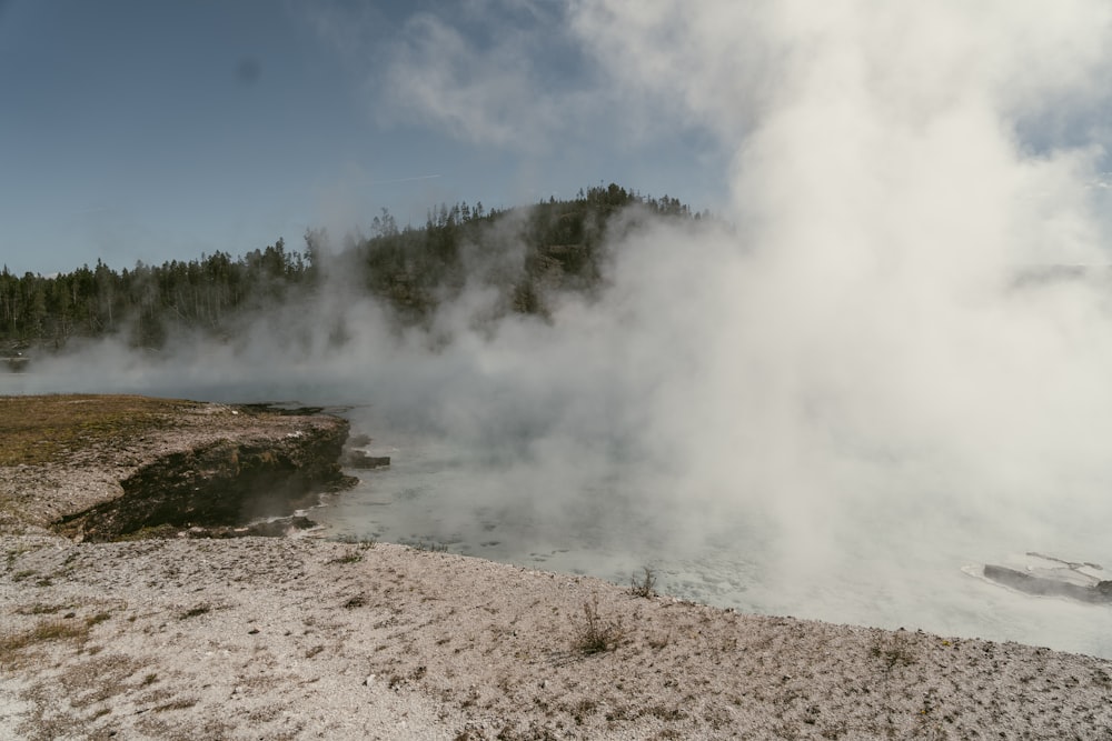 steam rises from the ground near a body of water
