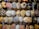 A collection of intricately designed traditional hats, adorned with ornate embroidery and vibrant patterns. The hats feature various embellishments such as beads, sequins, and tassels in a variety of colors including red, blue, gold, and white. They are displayed in a well-organized manner, showcasing their detailed craftsmanship.