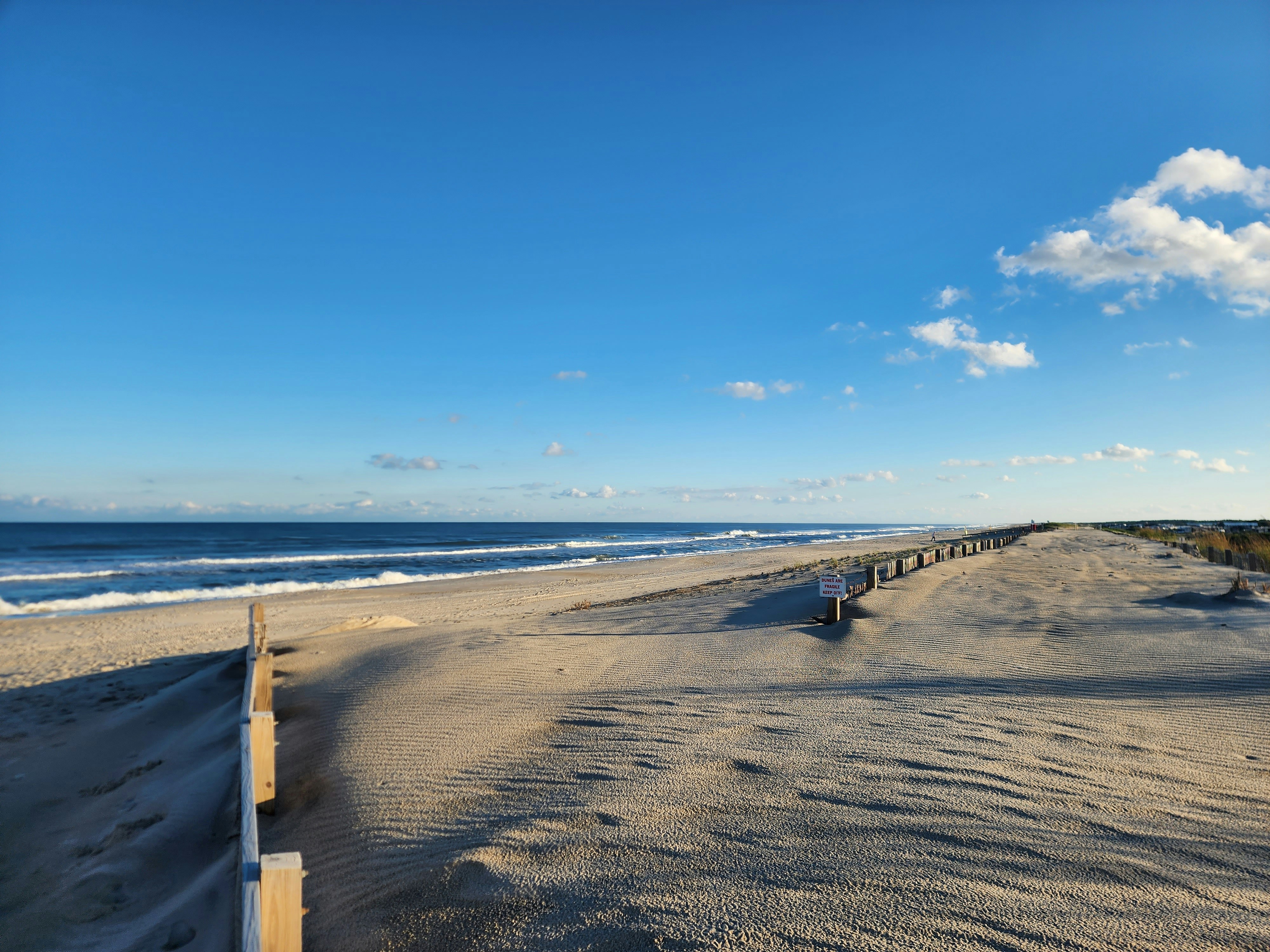 a sandy beach next to the ocean under a blue sky