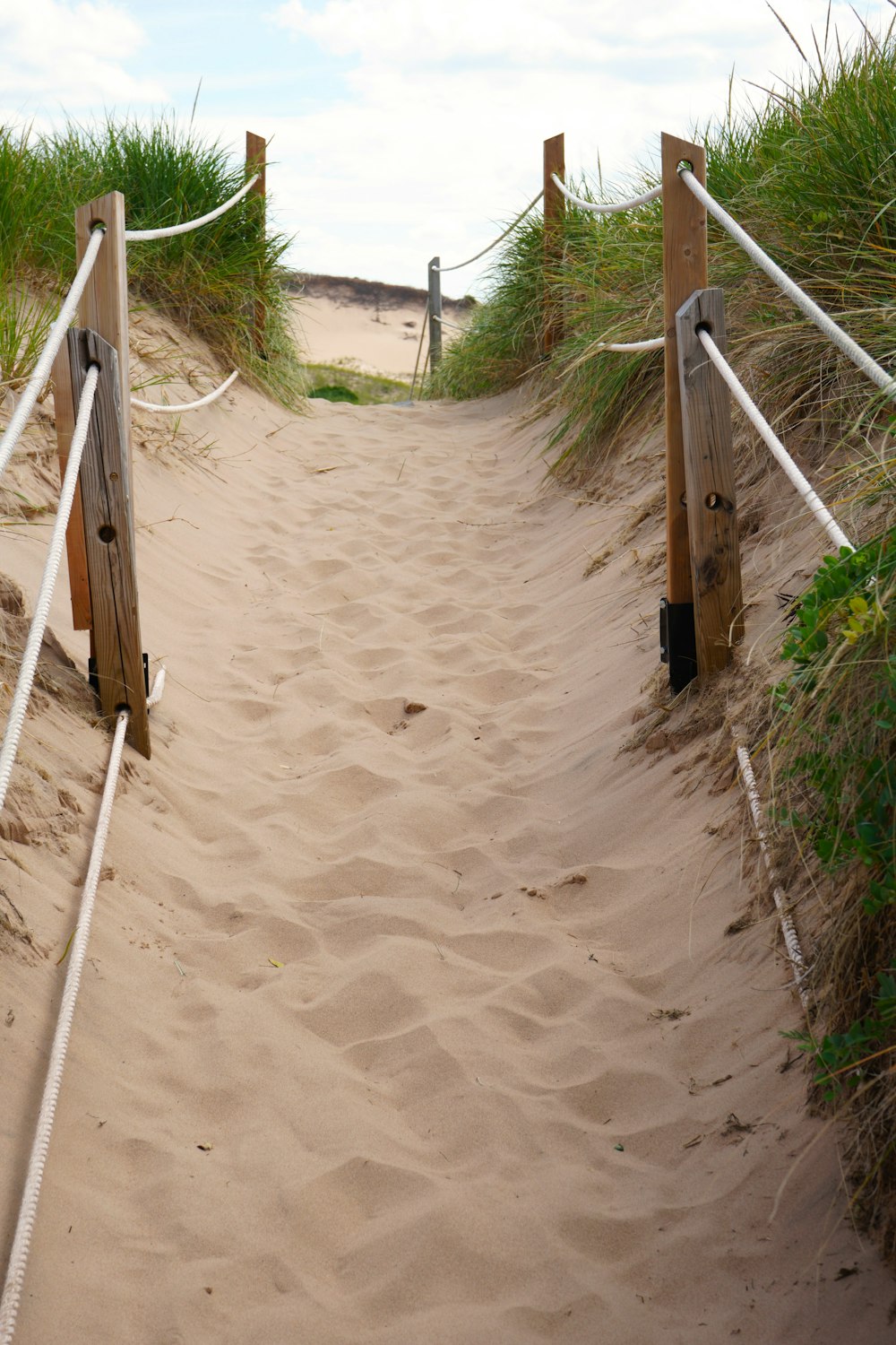 a wooden gate leading to a sandy beach