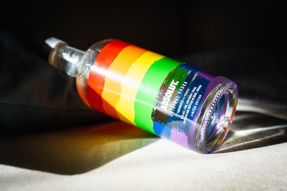 a multicolored bottle of water sitting on a bed