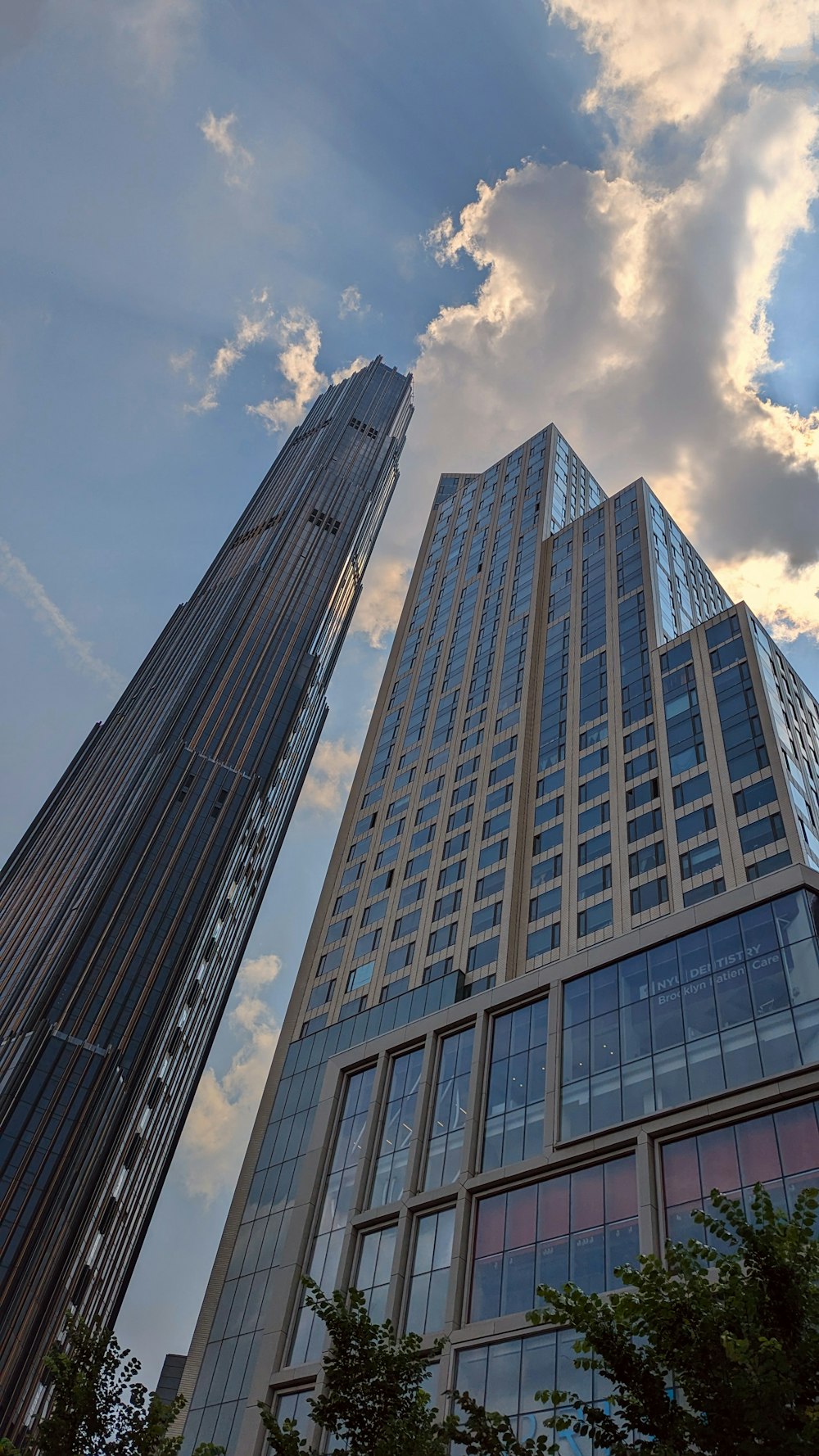 two tall skyscrapers against a cloudy blue sky