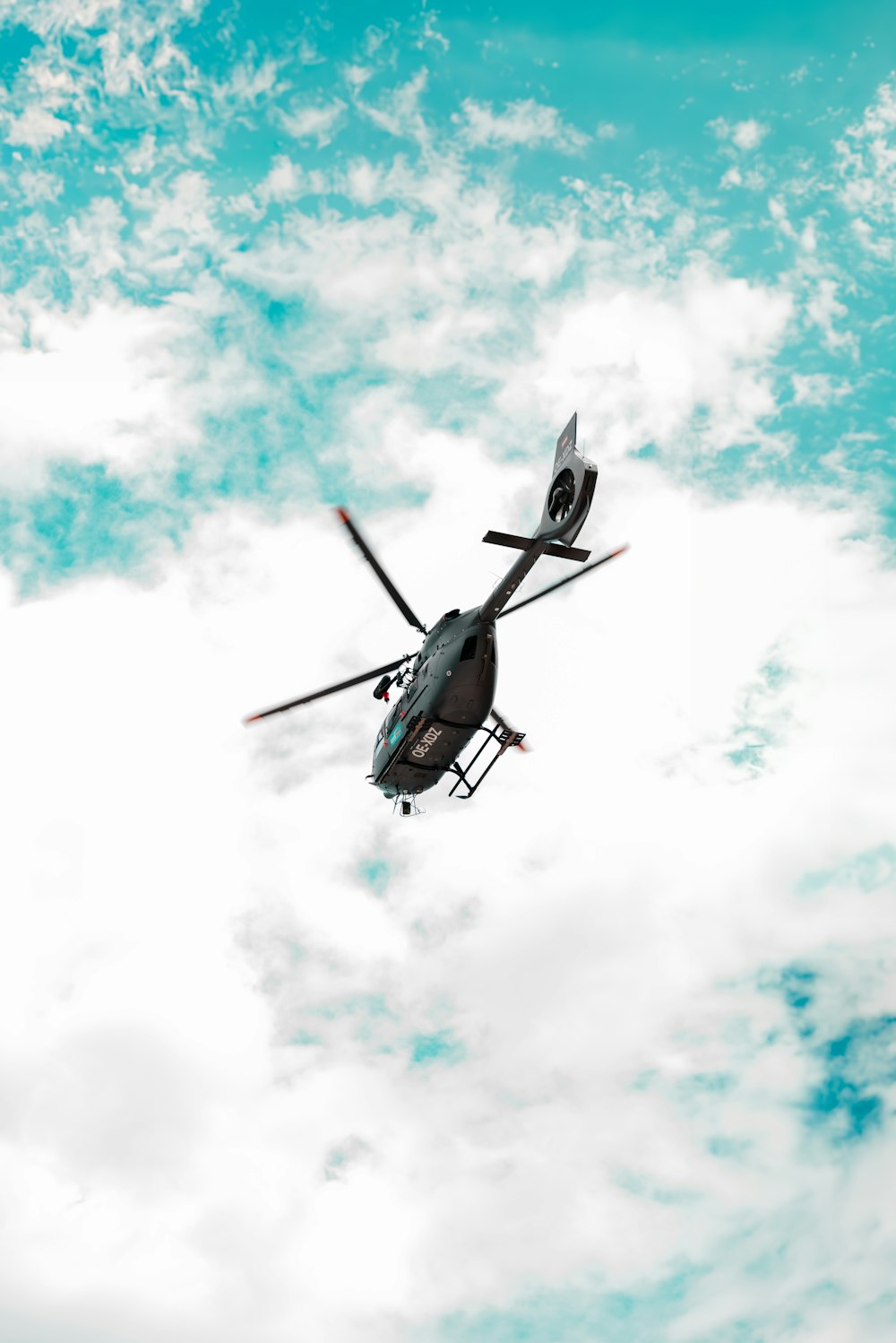 a helicopter flying through a cloudy blue sky