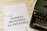 A sheet of paper with the words 'FAMILY BONDING ACTIVITIES' printed in bold, placed on a white wooden surface. There is a white pen next to the paper and a black typewriter partially visible on the right side.