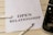 A white piece of paper laid on a wooden surface with the words 'OPEN RELATIONSHIP' printed on it. A fountain pen with a silver and black design is placed near the paper. Part of a typewriter is visible on the right side.