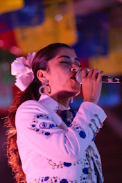 a woman in a white suit singing into a microphone