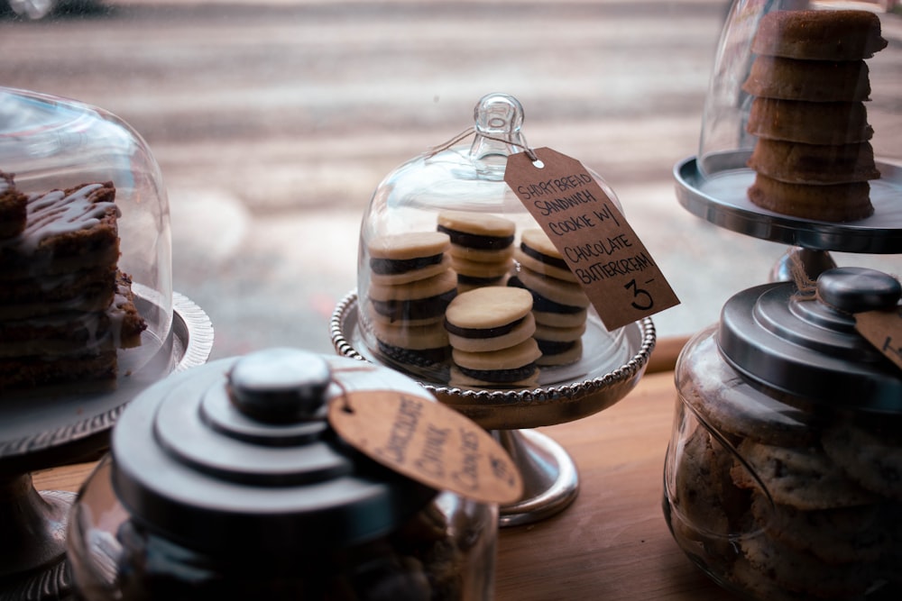 a table topped with cakes and cookies under a glass dome