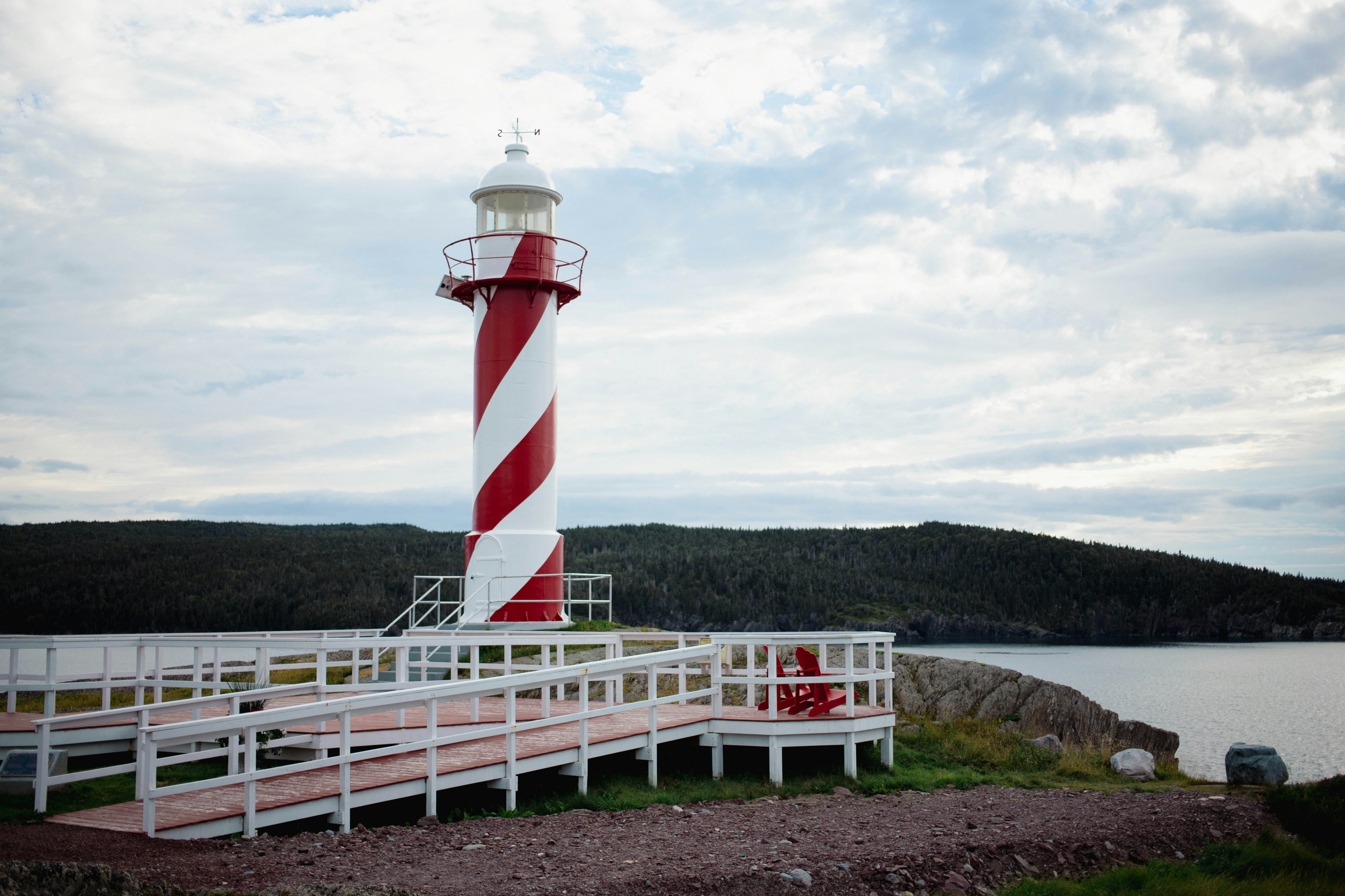 A red and white lighthouse sitting on top of a pier photo – Free ...
