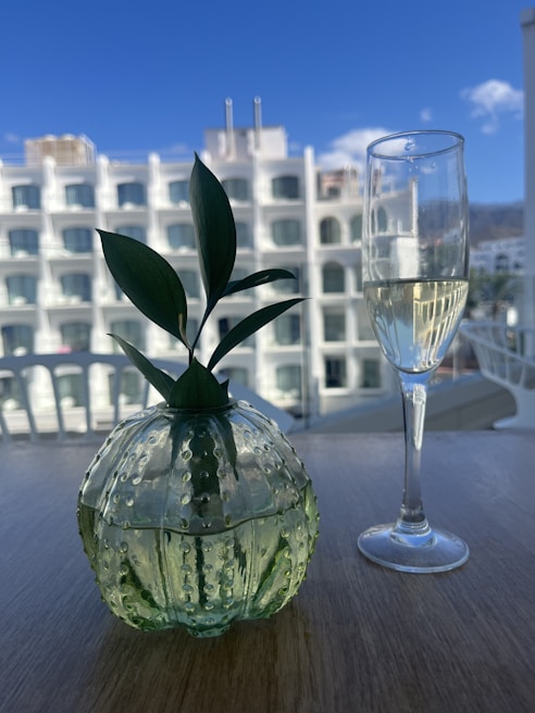 Close-up of a champagne gold accent vase with fresh green sage leaves on a minimalist wooden table