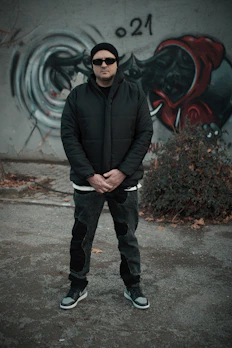 A stylish red and black coat hanging on a graffiti-covered wall.