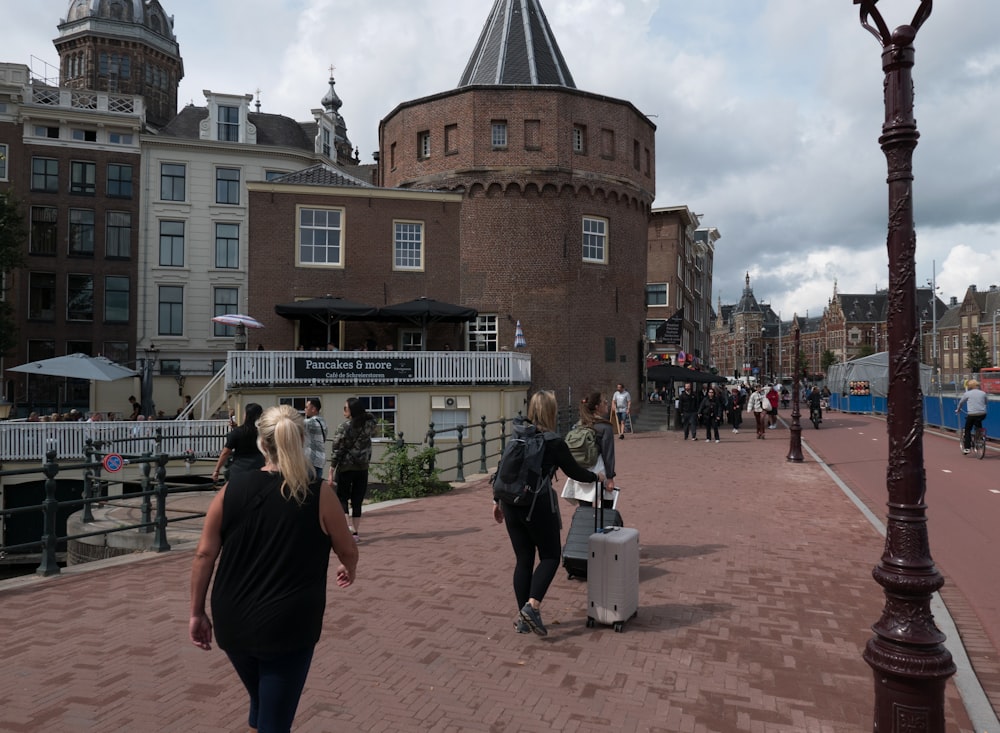 a group of people walking down a street next to tall buildings