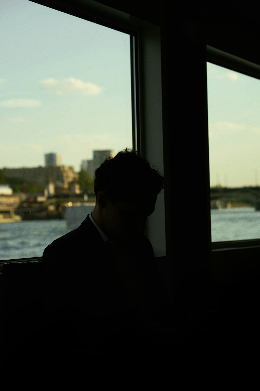 a man looking out of a window at a body of water