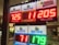 A signboard inside a convenience store displays the current jackpot amounts for various lottery games. There are bright, illuminated numbers in red and green showing the prize amounts: Powerball is at 725 million, Super Lotto Plus at 11 million, Mega Millions at 205 million, Fantasy 5 at 71 thousand, and Daily Derby at 179. In the background, shelves with various drinks and products are visible, along with promotional posters.