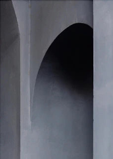 Architectural composition showing the bag framed by large shadows, intense natural light, and muted olive tones