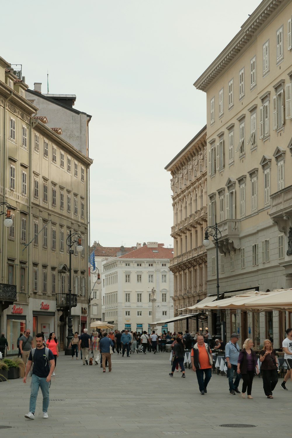 a group of people walking down a street next to tall buildings