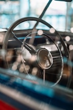 A close-up shot of a vintage custom car’s steering wheel with sunlight reflecting off the polished chrome.