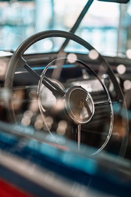 A close-up shot of a vintage custom car’s steering wheel with sunlight reflecting off the polished chrome.
