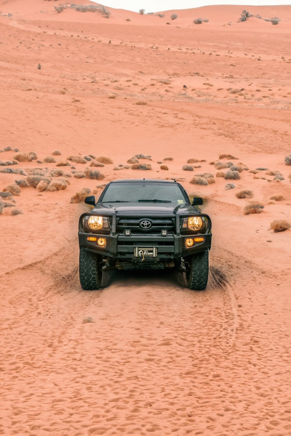 a black truck driving through a desert area