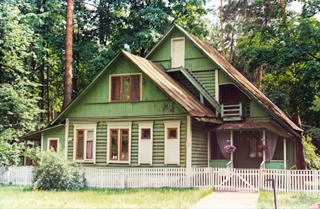 a green house with a white picket fence