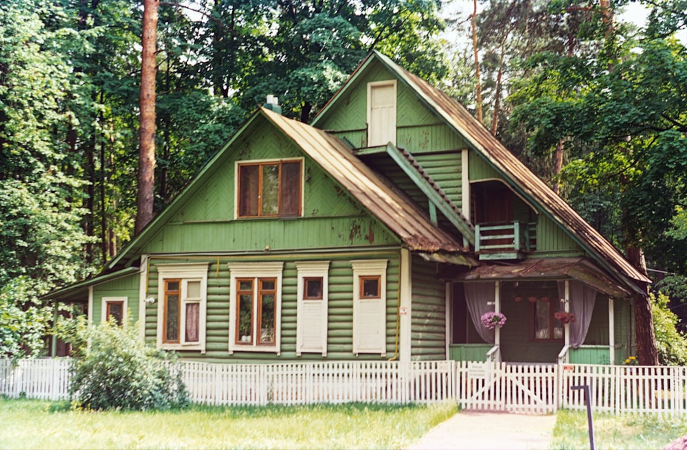 a green house with a white picket fence