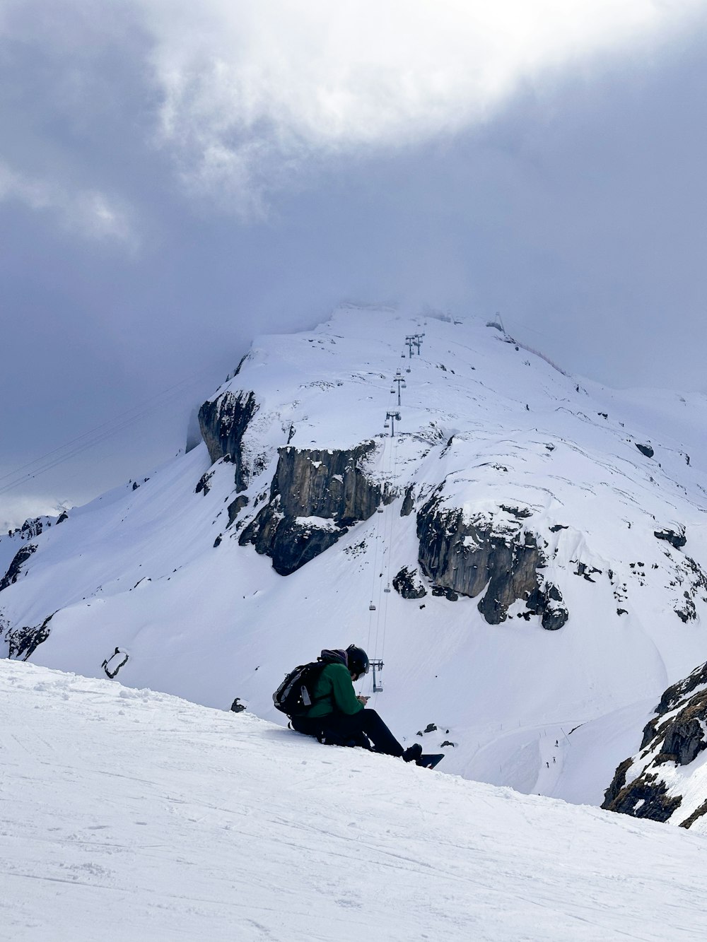 a man sitting on top of a snow covered slope