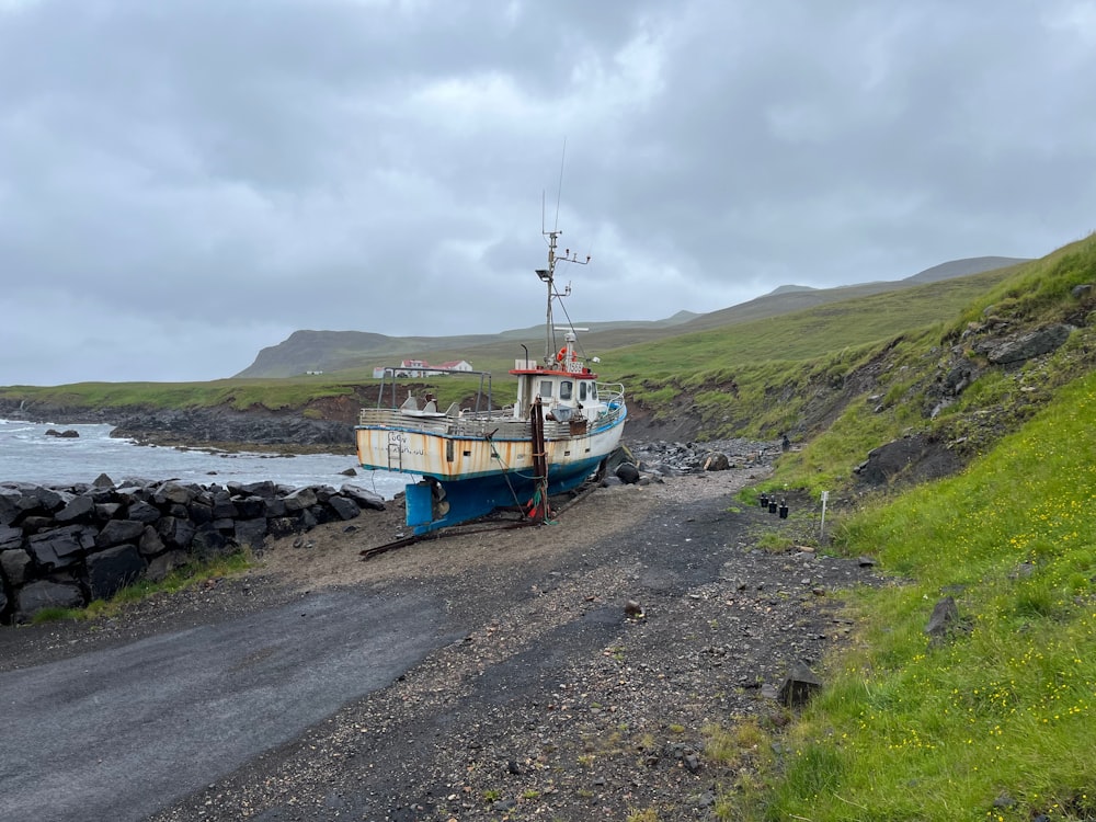 a boat sitting on top of a dirt road next to a body of water