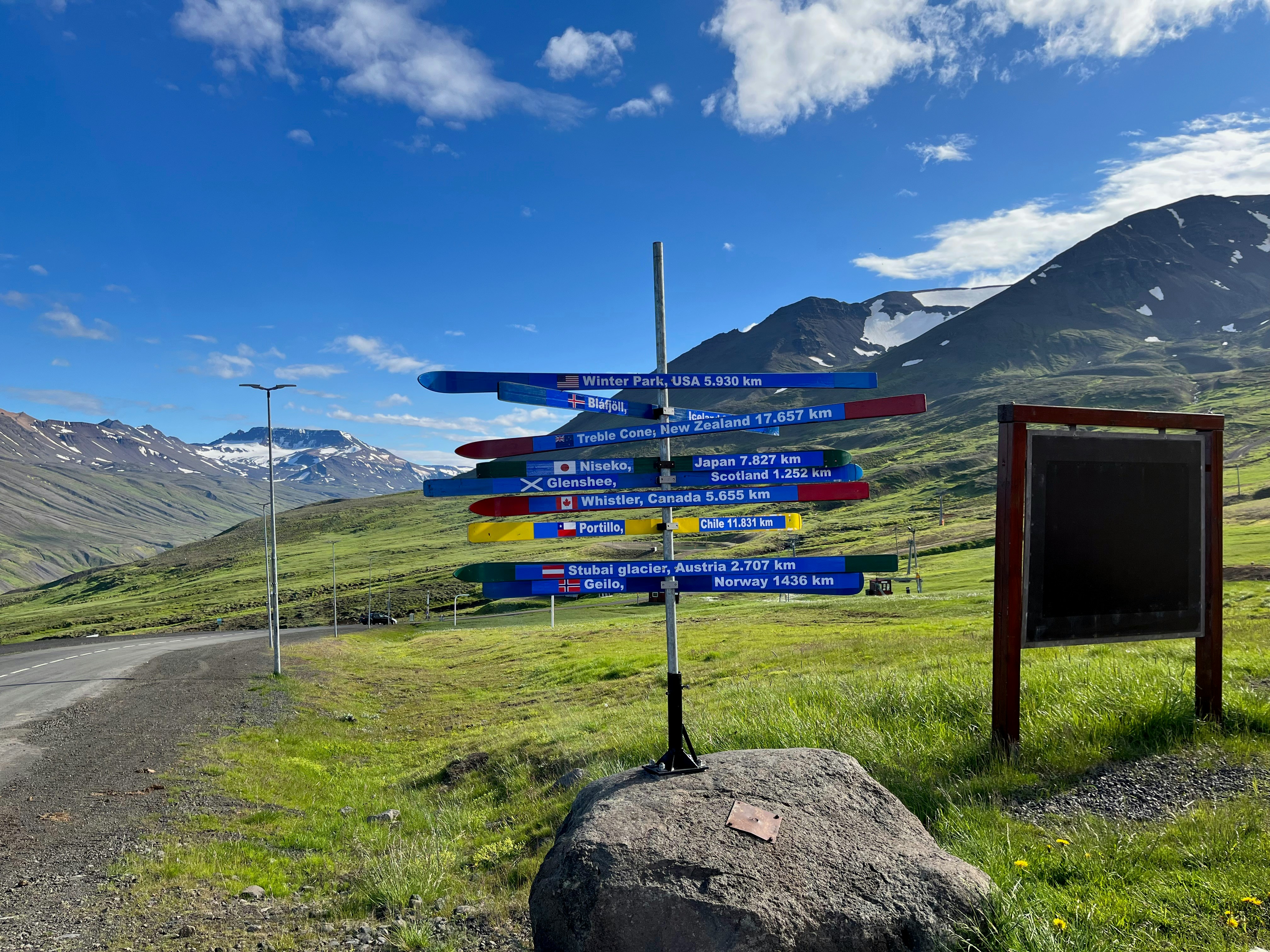 a bunch of signs on a pole by a road