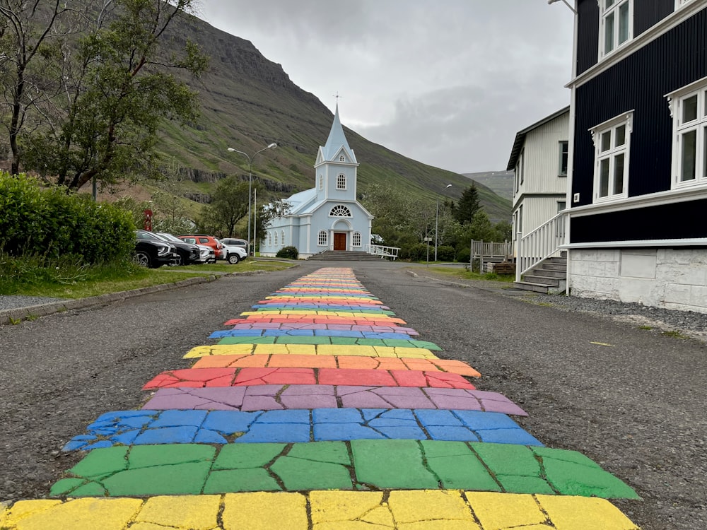 a rainbow painted road with a church in the background