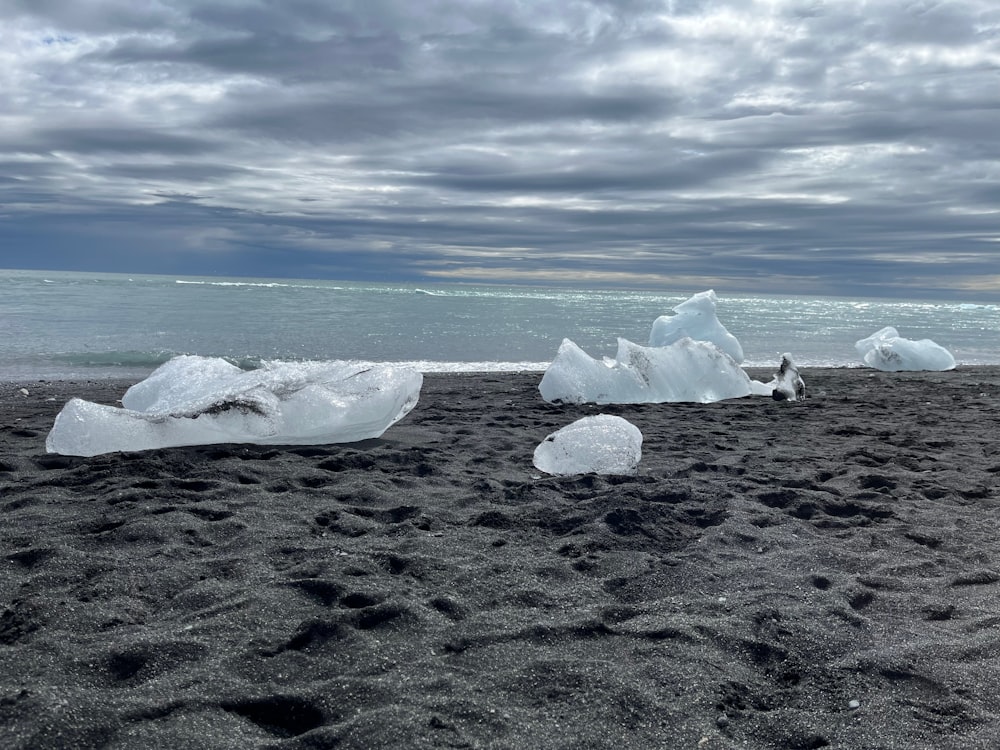 icebergs on a beach with a cloudy sky in the background
