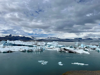 Tourists exploring a serene glacier lagoon dotted with floating icebergs.
