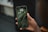 A hand holds a smartphone displaying the lock screen showing the time as 1:11 on Tuesday, 9 May, with a background of green leaves.