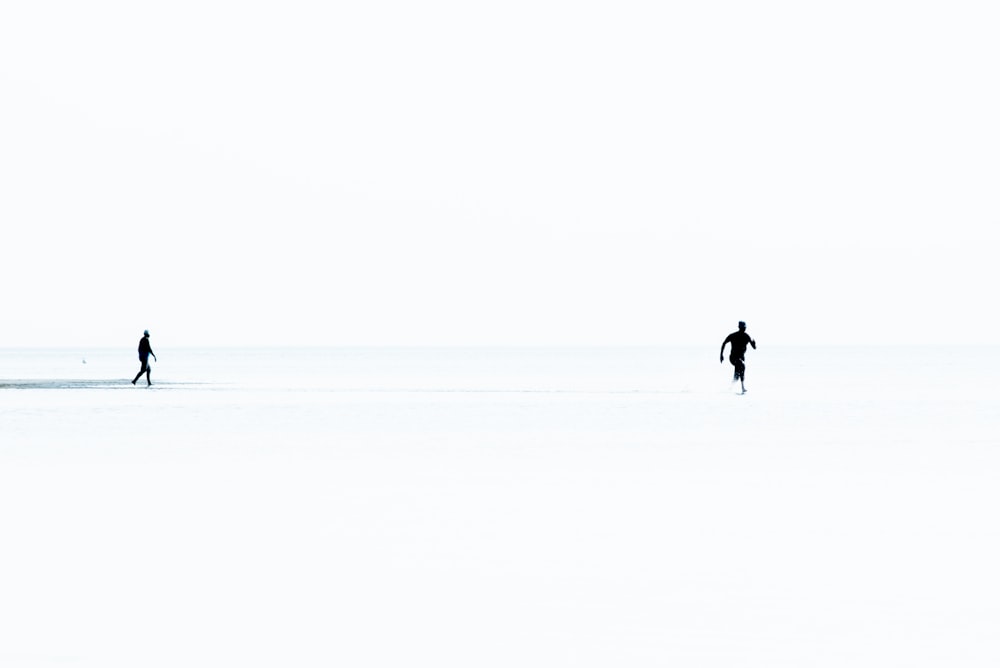 a couple of people walking across a snow covered field