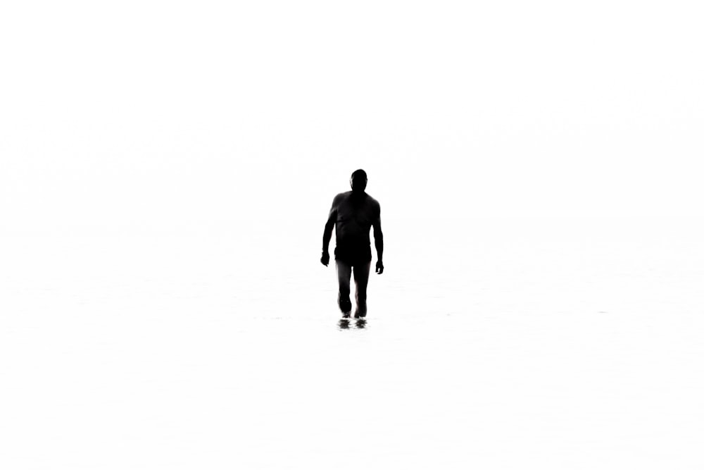 a silhouette of a man walking across a white floor