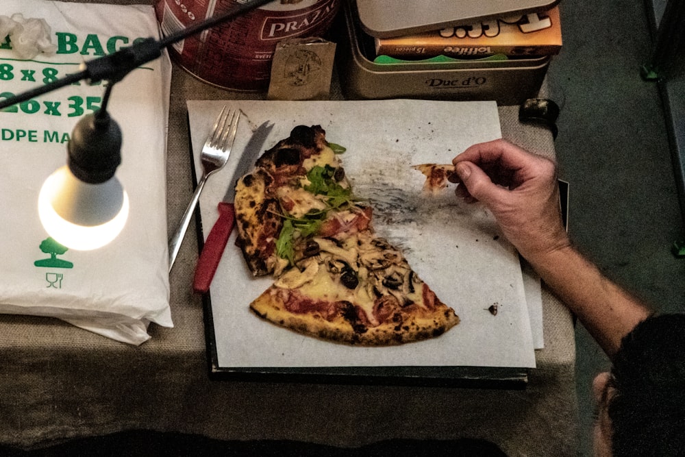 a person eating a slice of pizza from a box