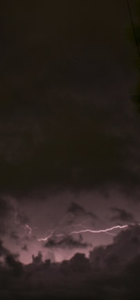Dark clouds dominate the sky with a visible streak of lightning illuminating parts of the scene. The atmosphere is moody and intense, with stormy weather evident.
