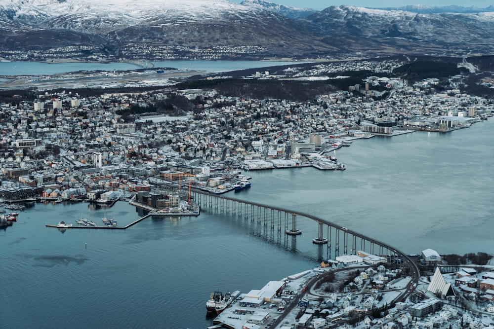 an aerial view of a city with a bridge and mountains in the background