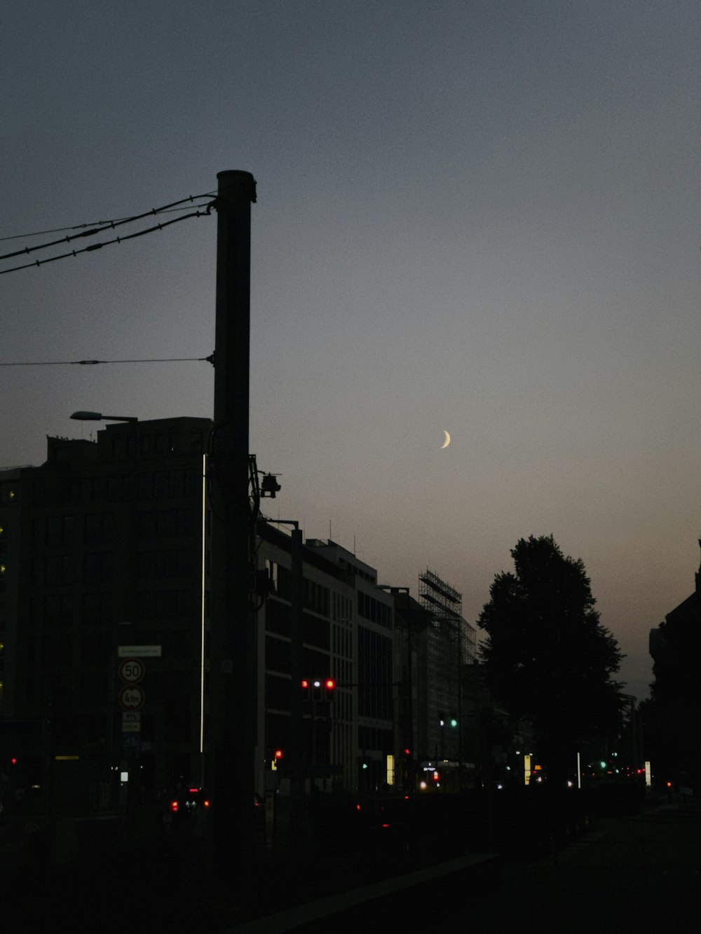 a city street at night with the moon in the sky