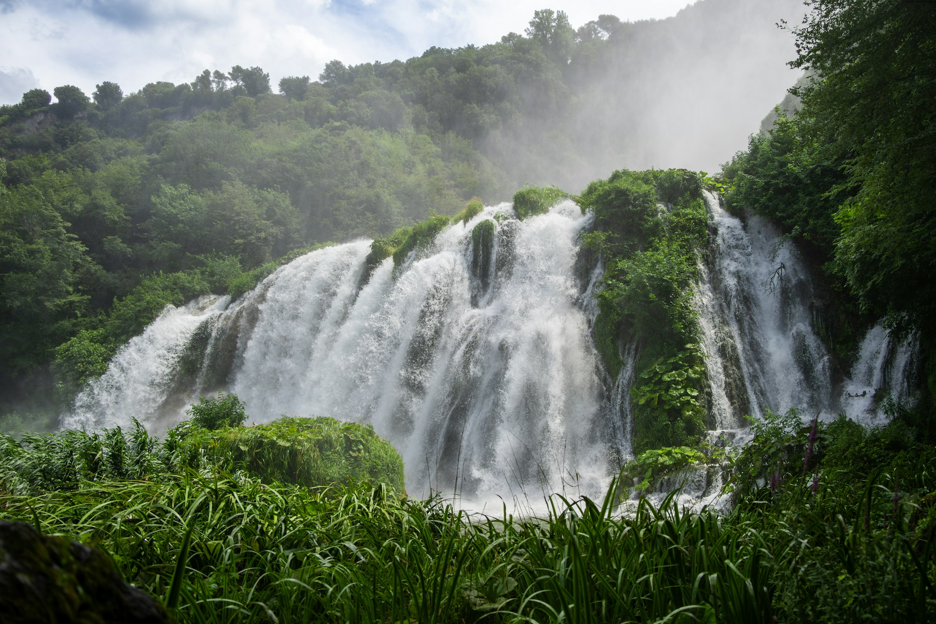 a large waterfall in the middle of a forest