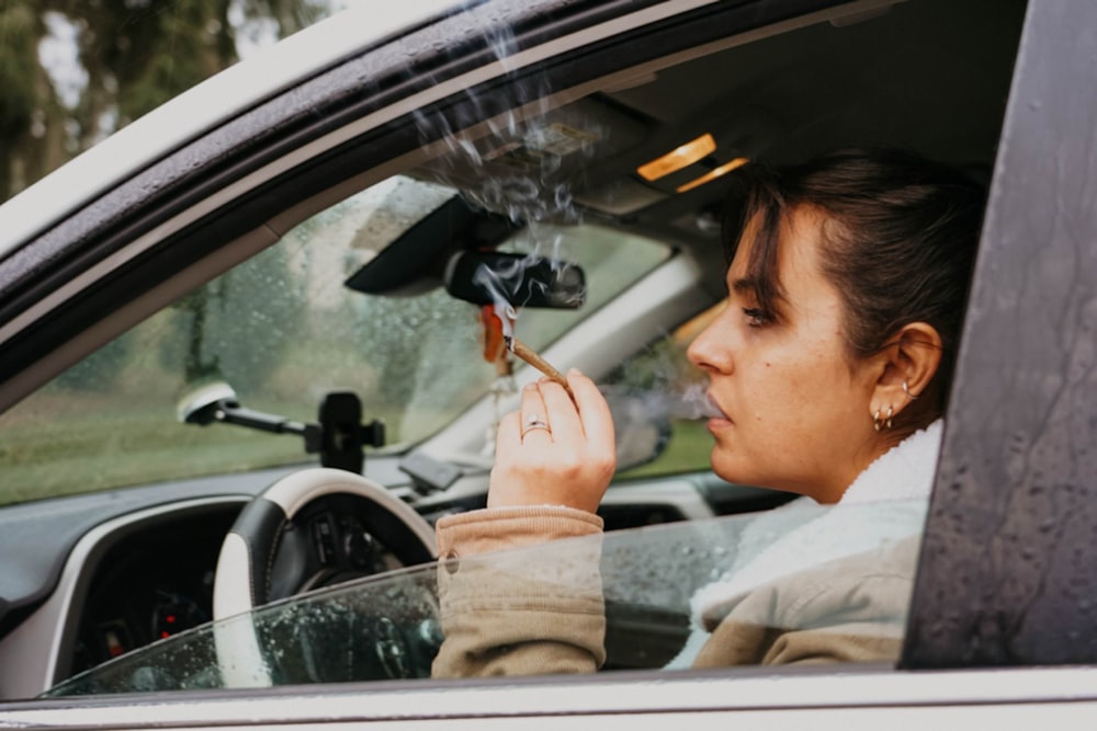 Una mujer fumando un cigarrillo en un coche