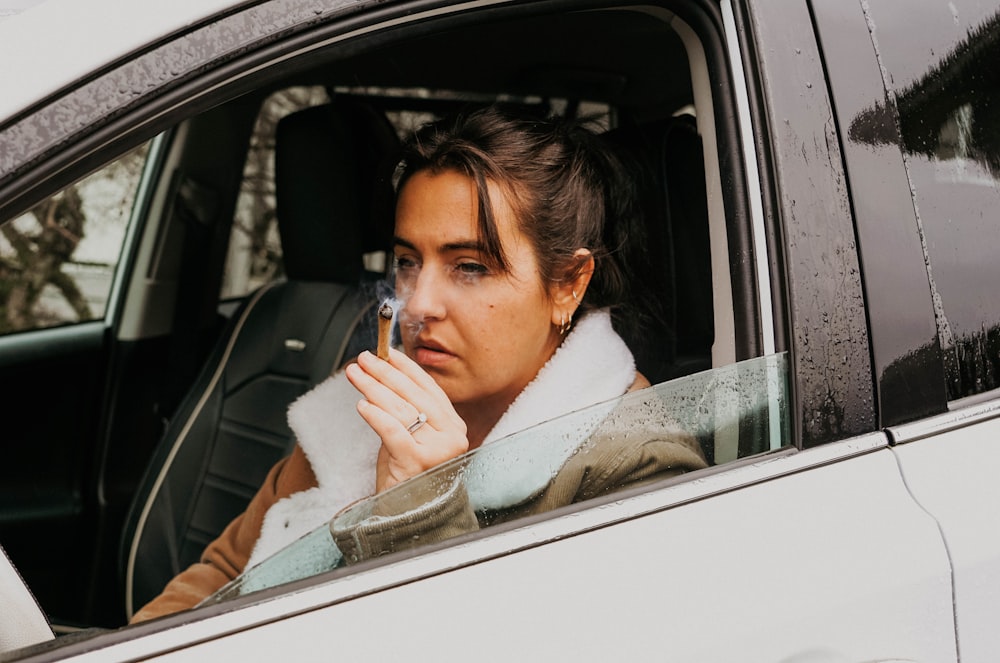 a woman sitting in a car smoking a cigarette