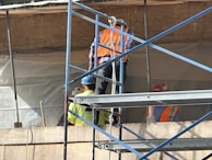 Deux hommes debout en haut d’un échafaudage.
